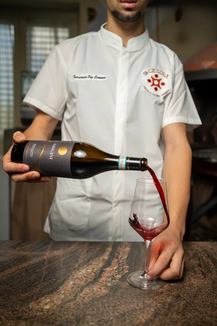 Il cameriere Luca versa un calice di vino rosso