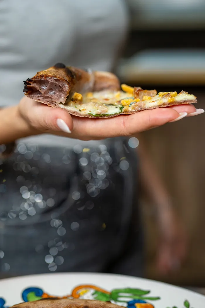 Una fetta di pizza gourmet gustata a mano